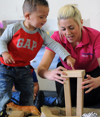 child with building blocks and carer helping